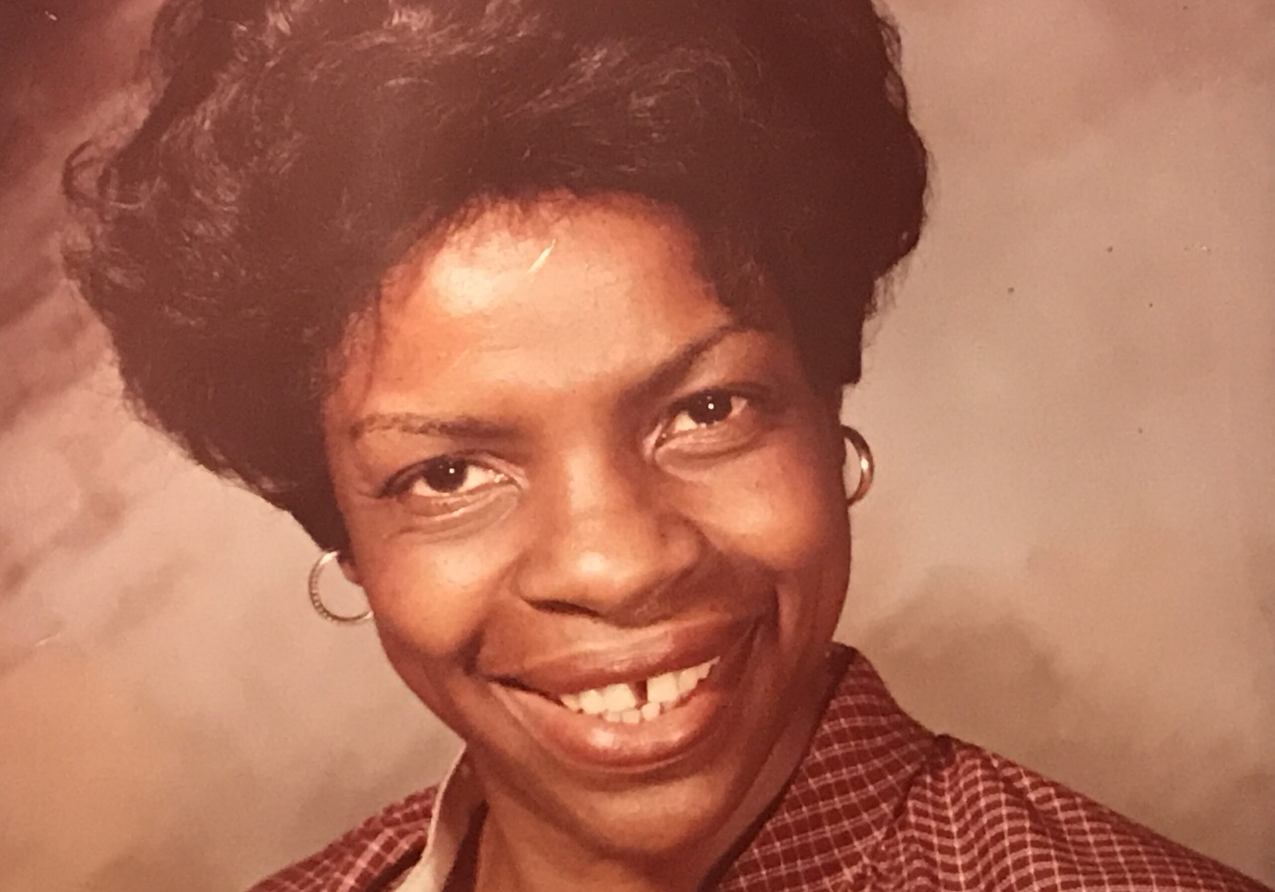 Woman wearing checkered jacket and earrings.
